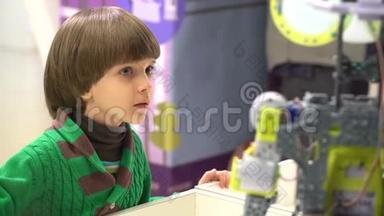 机器人和孩子。 找机器人的男孩。 孩子看机器人。 男孩在展览会上看机器人技术。 男孩和男孩